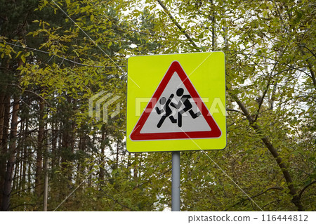 Road sign, installed near schools. Be careful, children. Yellow square, with a red triangle, white, with the image of running people 116444812