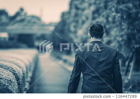 A middle-aged businessman walking down the street in a suit A middle-aged businessman walking down the street in a suit 116447289