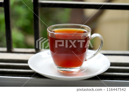 FULL CUP RED LIQUOR TEA IN TRANSPARENT IN WINDOW AS MORNING TEA 116447542