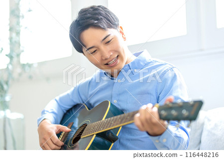 A young man playing the guitar 116448216