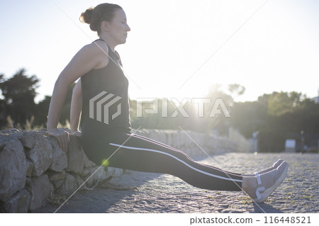 A woman is doing a push up on a stone wall A woman is doing a push up on a stone wall 116448521