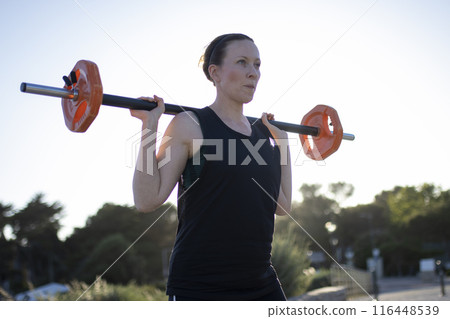 A woman is lifting a weight in the sun A woman is lifting a weight in the sun 116448539