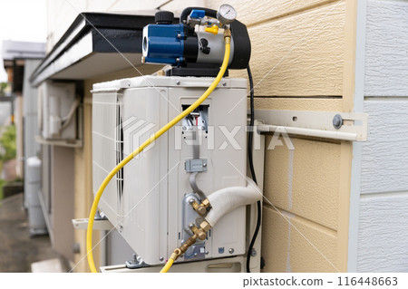 Vacuuming the outdoor unit of a home air conditioner Vacuuming the outdoor unit of a home air conditioner 116448663