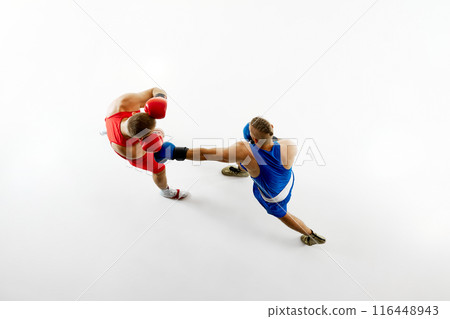 Aerial view of two men boxing, showcasing blue fighter's punch aimed at fighter in red uniform against white studio background. Aerial view of two men boxing, showcasing blue fighter's punch aimed at fighter in red uniform against white studio background. 116448943