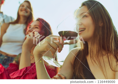 Portrait of festive toast among friends, men and women, their drinks glistening in warm rays of sun. Hot summer holidays. Portrait of festive toast among friends, men and women, their drinks glistening in warm rays of sun. Hot summer holidays. 116449000