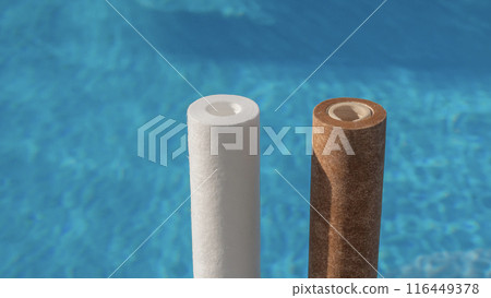 Two water filter cartridges, one clean and one dirty, in front of a swimming pool. 116449378