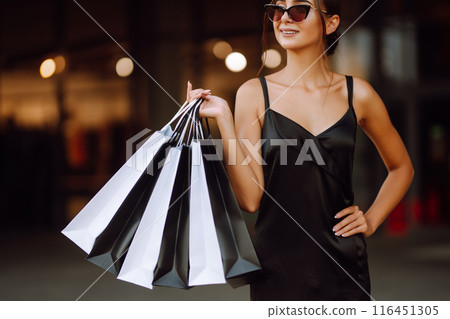 Shopping bags in the hands. Fashion woman with packages after shopping. Black friday, sale. 116451305