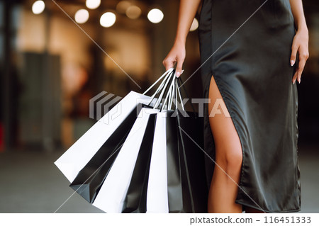 Shopping bags in the hands. Fashion woman with packages after shopping. Black friday, sale. 116451333