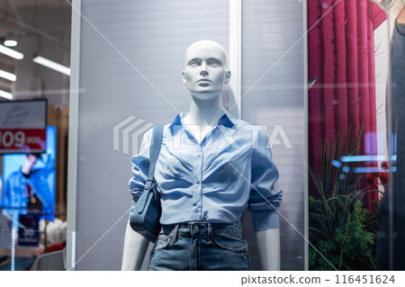 Mannequin in store window wears blue shirt and jeans, symbolizing fashion 116451624