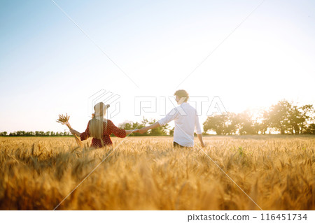 Young happy couple hugging on a wheat field, on the sunset. Enjoying time together. Young happy couple hugging on a wheat field, on the sunset. Enjoying time together. 116451734