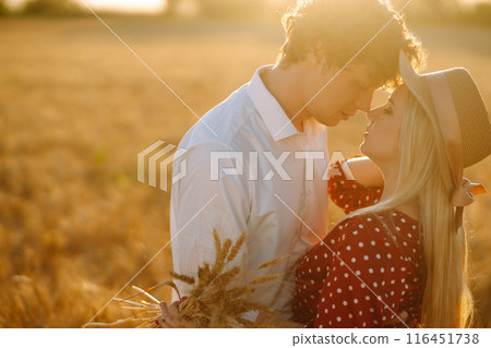 Portrait of young happy couple hugging on the field on the sunset. Enjoying time together. Portrait of young happy couple hugging on the field on the sunset. Enjoying time together. 116451738