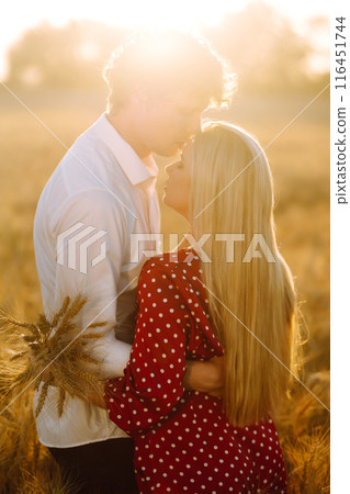 Young happy couple hugging on a wheat field, on the sunset. Enjoying time together. 116451744