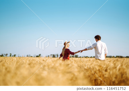 Young happy couple hugging on a wheat field, on the sunset. Enjoying time together. Young happy couple hugging on a wheat field, on the sunset. Enjoying time together. 116451752