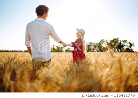 Young happy couple hugging on a wheat field, on the sunset. Enjoying time together. Young happy couple hugging on a wheat field, on the sunset. Enjoying time together. 116451779