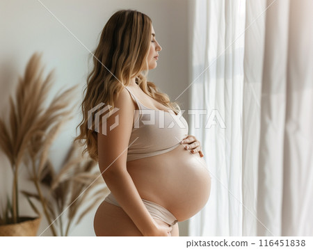 pregnant woman standing hands on your stomach Turn to look out the window. pregnant woman standing hands on your stomach Turn to look out the window. 116451838