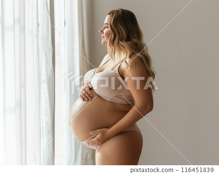 pregnant woman standing hands on your stomach Turn to look out the window. 116451839