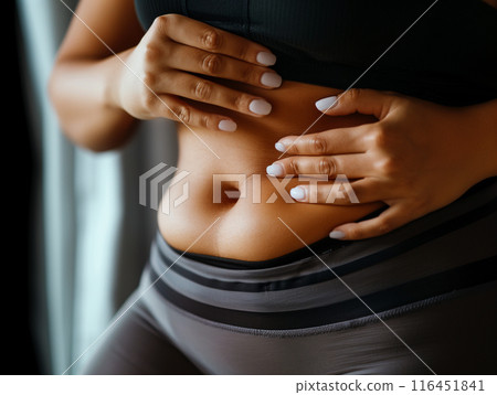 Fat belly of a woman. female hand of excessive fat on the belly. diet lifestyle concept to shrink belly and form healthy abdominal muscles. 116451841