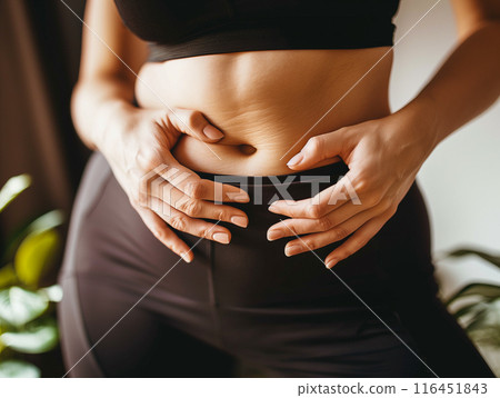 Fat belly of a woman. female hand of excessive fat on the belly. diet lifestyle concept to shrink belly and form healthy abdominal muscles. Fat belly of a woman. female hand of excessive fat on the belly. diet lifestyle concept to shrink belly and form healthy abdominal muscles. 116451843