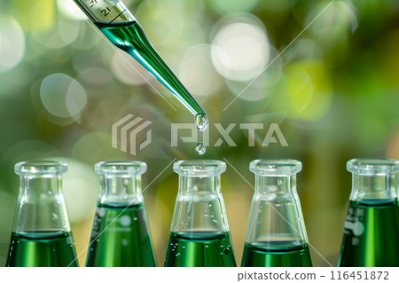 Close-up Science experiment equipment. Sample dripping pipettes into Erlenmeyer bottles containing chemical green Close-up Science experiment equipment. Sample dripping pipettes into Erlenmeyer bottles containing chemical green 116451872