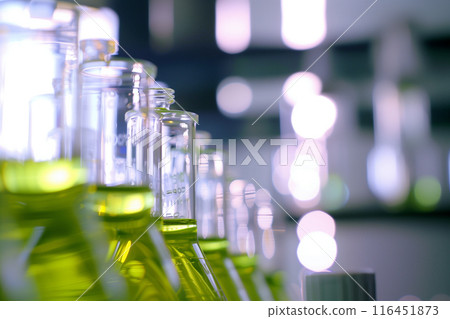 Close-up Science experiment equipment. Sample dripping pipettes into Erlenmeyer bottles containing chemical green Close-up Science experiment equipment. Sample dripping pipettes into Erlenmeyer bottles containing chemical green 116451873
