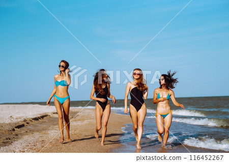 Four young girls having fun on the beach. Group of girlfriends enjoying on beach holiday. Summer lifestyle. 116452267