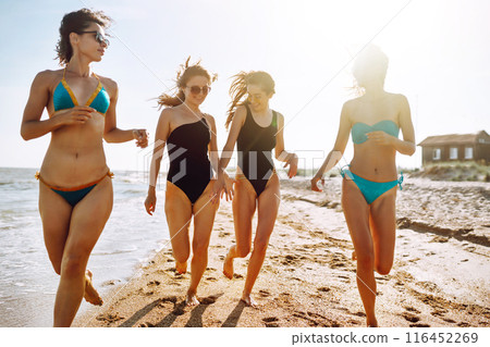 Four young girls having fun on the beach. Group of girlfriends enjoying on beach holiday. Summer lifestyle. Four young girls having fun on the beach. Group of girlfriends enjoying on beach holiday. Summer lifestyle. 116452269