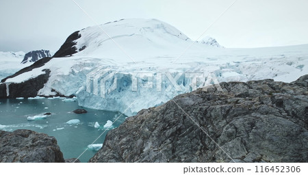 Antarctica coastline bay with rocks and glacier towering over polar ocean water. Snow covered mountains, calving ice floes. Amazing winter landscape. Travel Antarctica. Explore South Pole wild nature Antarctica coastline bay with rocks and glacier towering over polar ocean water. Snow covered mountains, calving ice floes. Amazing winter landscape. Travel Antarctica. Explore South Pole wild nature 116452306