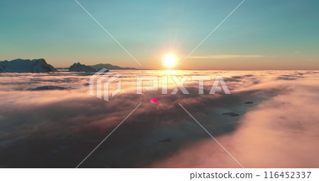 Amazing bright cloudscape morning colorful scene. Beautiful ocean of fog at sunrise. Sun shines brightly over towering snow covered mountain range. Aerial drone footage fly high over clouds landscape Amazing bright cloudscape morning colorful scene. Beautiful ocean of fog at sunrise. Sun shines brightly over towering snow covered mountain range. Aerial drone footage fly high over clouds landscape 116452337