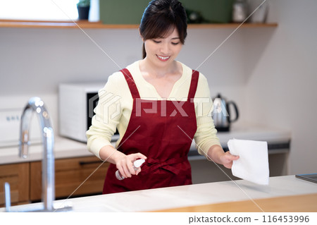 穿著圍裙的中年婦女在廚房擦拭乾淨 穿著圍裙的中年婦女在廚房擦拭乾淨 116453996