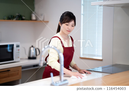 穿著圍裙的中年婦女在廚房擦拭乾淨 穿著圍裙的中年婦女在廚房擦拭乾淨 116454003