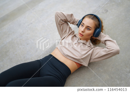 Young woman in sports outfit doing exercises outdoors in morning. Concept of sports, yoga or fitness Young woman in sports outfit doing exercises outdoors in morning. Concept of sports, yoga or fitness 116454013
