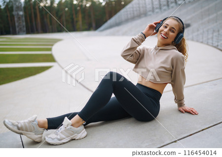Young woman in sports outfit doing exercises outdoors in morning. Concept of sports, yoga or fitness Young woman in sports outfit doing exercises outdoors in morning. Concept of sports, yoga or fitness 116454014