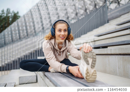 Young woman in sports outfit doing exercises outdoors in morning. Concept of sports, yoga or fitness 116454030