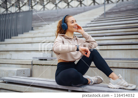 Young woman in sports outfit doing exercises outdoors in morning. Concept of sports, yoga or fitness Young woman in sports outfit doing exercises outdoors in morning. Concept of sports, yoga or fitness 116454032