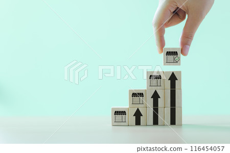 Business growth and franchise expansion concept. Hand stacking wooden blocks with store icons, depicting strategy of business growth and franchise expansion. increasing store on digital upward trend 116454057