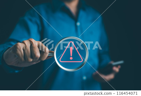 Warning alert system concept. Man holding magnifying glass focused on a glowing exclamation mark warning sign red. hack on computer network, crime virus, Malicious software, Cyber security, illegal, Warning alert system concept. Man holding magnifying glass focused on a glowing exclamation mark warning sign red. hack on computer network, crime virus, Malicious software, Cyber security, illegal, 116454071