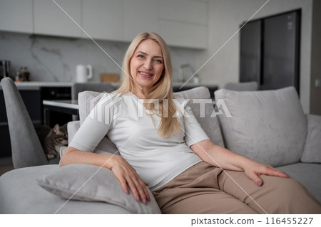 A woman is peacefully lounging on a couch in a contemporary home with simple and clean design A woman is peacefully lounging on a couch in a contemporary home with simple and clean design 116455227