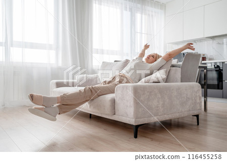 A senior woman is enjoying a peaceful moment while relaxing on a sofa at her home A senior woman is enjoying a peaceful moment while relaxing on a sofa at her home 116455258