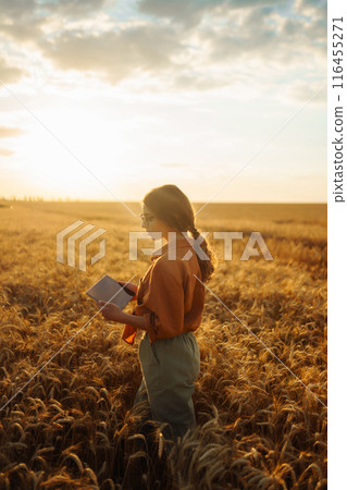Farmer- woman on wheat field with tablet in his hands. Smart farm. Agriculture, gardening concept. 116455271