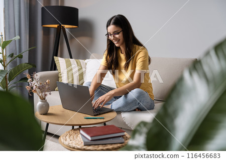 Study chic. This girl is all smiles as she tackles her homework from the comfort of her couch Study chic. This girl is all smiles as she tackles her homework from the comfort of her couch 116456683