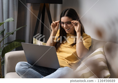 Kicking off the new school year right. A young woman vibes out in her cozy spot, diving into homework on her laptop Kicking off the new school year right. A young woman vibes out in her cozy spot, diving into homework on her laptop 116456689