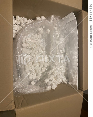 Cardboard box being filled with packing peanuts 116457119