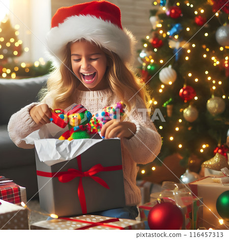 Excited girl in santa hat discovers colorful toys in her christmas gift box, capturing the joy and anticipation of the holiday morning 116457313