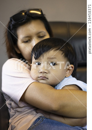 Horizontal portrait of woman sitting on armchair with her little infant on her arm. Horizontal portrait of woman sitting on armchair with her little infant on her arm. 116458371