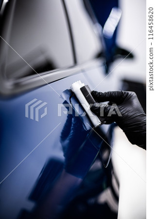 Image shows a person applying a ceramic coating to the surface of a blue car Image shows a person applying a ceramic coating to the surface of a blue car 116458620