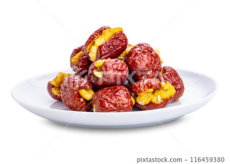 Pile of dried pitted chinese jujube stuffed with crunchy walnut in white ceramic plate. 116459380