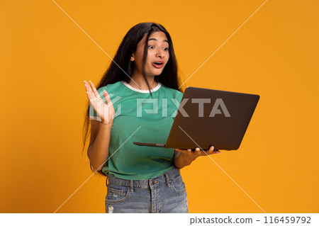 Young girl student using laptop for online communication, education and freelance work against yellow studio background Young girl student using laptop for online communication, education and freelance work against yellow studio background 116459792