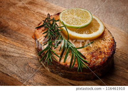 salmon steak, fried, on a cutting board, top view, rosemary, lemon and lime, homemade, one serving, no people, 116461910