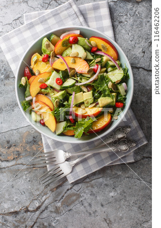 Vegetarian Peach Avocado Salad with red onion, chili, arugula, spinach and pumpkin seeds dressed with olive oil close-up in a bowl. Vertical top view 116462206