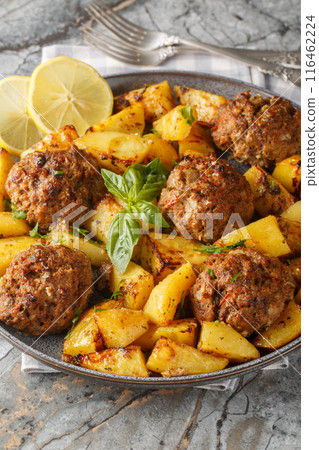 Bifteki is a Greek burger juicy and flavorful biftekia baked with crispy potatoes in a lemon olive oil sauce closeup on the plate. Vertical Bifteki is a Greek burger juicy and flavorful biftekia baked with crispy potatoes in a lemon olive oil sauce closeup on the plate. Vertical 116462224